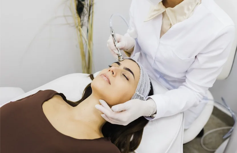 Skincare specialist performing a facial treatment on a patient using a specialized device for collagen induction therapy.