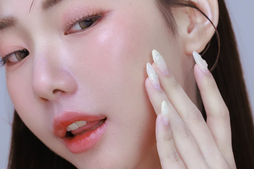 Close-up of a woman touching her smooth, radiant cheek showcasing luminous Glass Skin.
